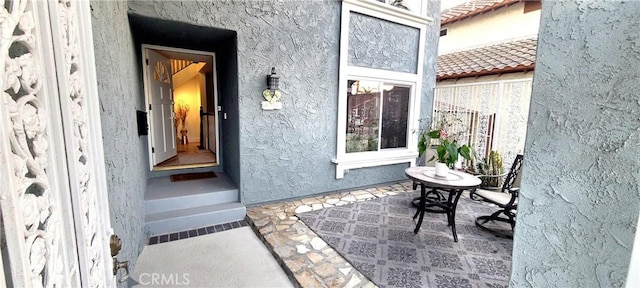 property entrance featuring a tile roof and stucco siding