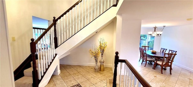 stairway featuring a towering ceiling, an inviting chandelier, baseboards, and tile patterned floors