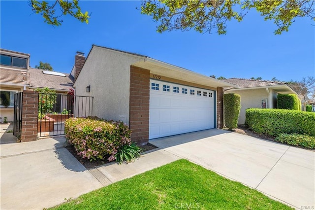 view of front of house featuring an attached garage, a chimney, concrete driveway, and stucco siding