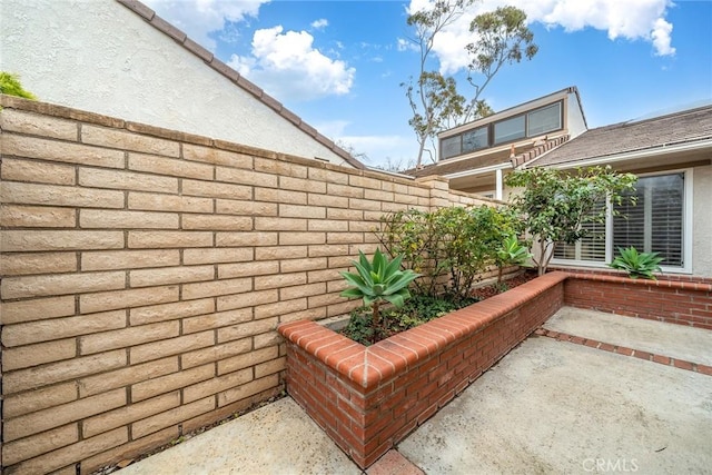 exterior space featuring brick siding, fence, and a patio