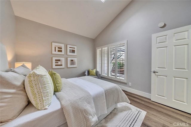 bedroom featuring high vaulted ceiling, baseboards, and wood finished floors