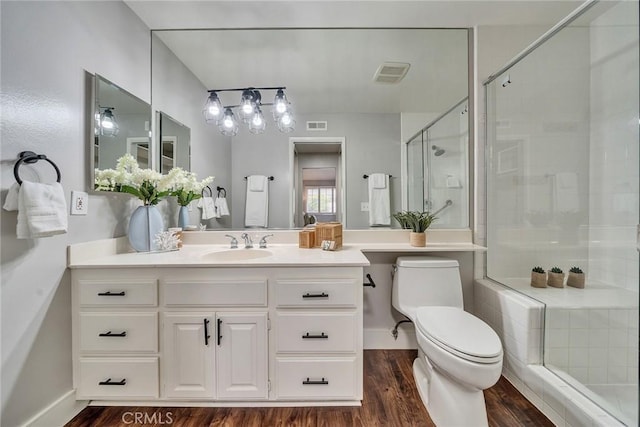 bathroom featuring toilet, wood finished floors, vanity, visible vents, and a shower stall