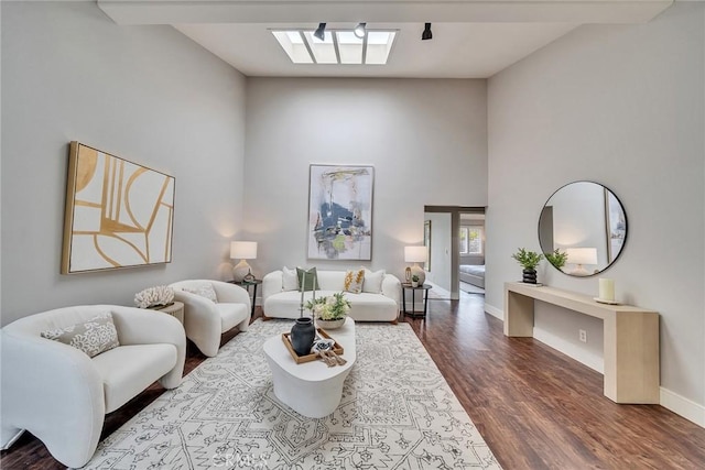 living room with dark wood-type flooring, a high ceiling, and baseboards