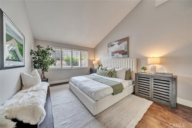 bedroom with high vaulted ceiling, baseboards, and wood finished floors