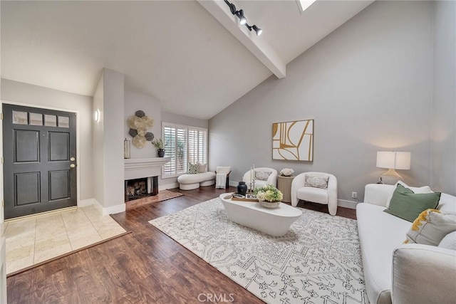 living area with high vaulted ceiling, dark wood-type flooring, a fireplace, baseboards, and beamed ceiling