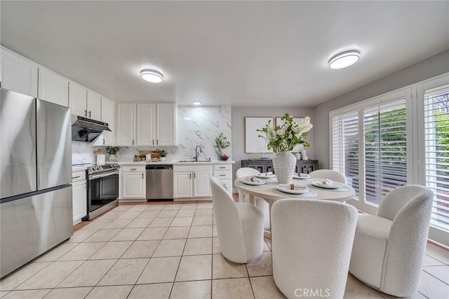 kitchen with light tile patterned floors, appliances with stainless steel finishes, light countertops, under cabinet range hood, and a sink