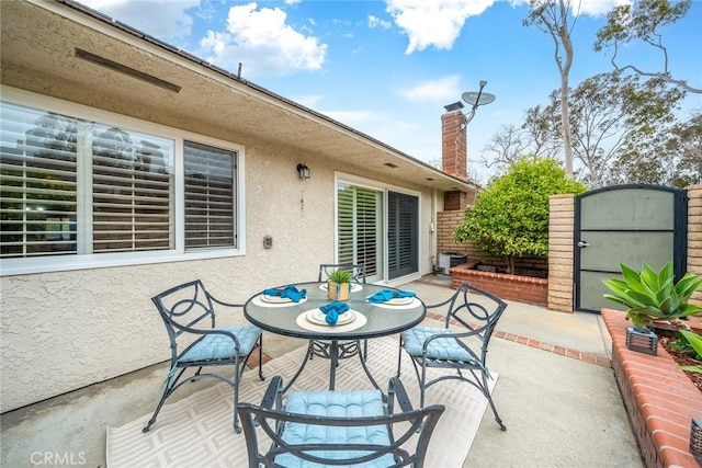 view of patio with central AC, outdoor dining space, and a gate