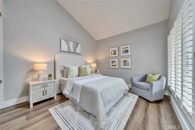 bedroom featuring vaulted ceiling, baseboards, and wood finished floors