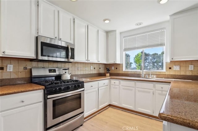 kitchen featuring appliances with stainless steel finishes, white cabinets, and a sink