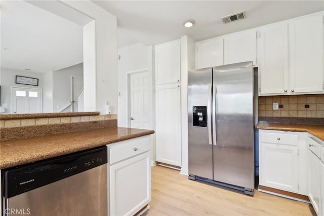 kitchen featuring appliances with stainless steel finishes, white cabinets, and visible vents