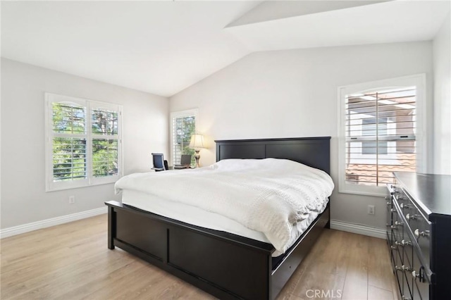 bedroom featuring vaulted ceiling, multiple windows, baseboards, and light wood-style floors