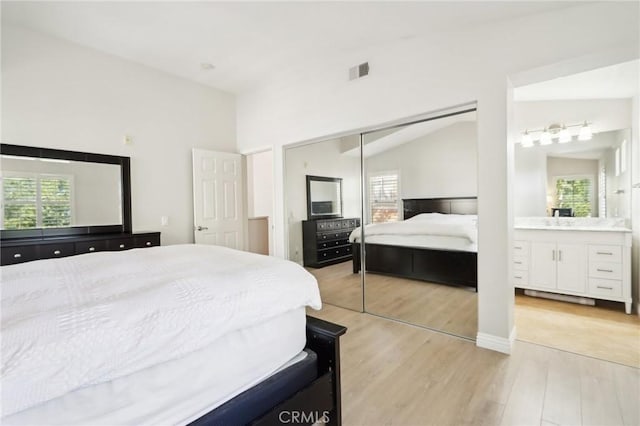 bedroom with lofted ceiling, connected bathroom, visible vents, a closet, and light wood finished floors