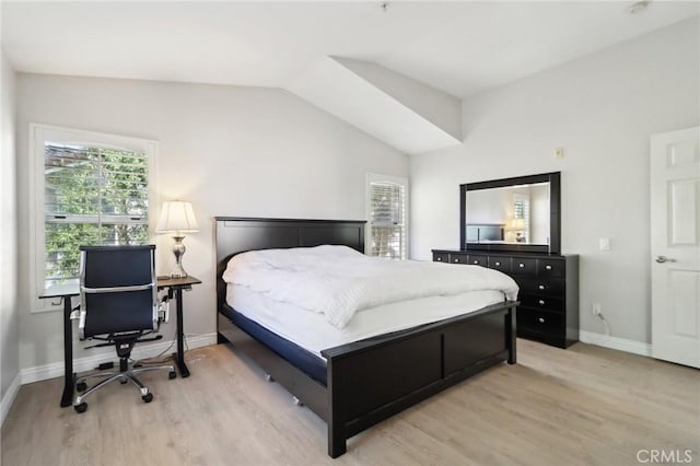 bedroom with baseboards, vaulted ceiling, and light wood finished floors