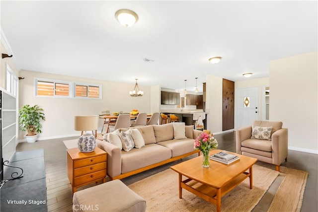 living room featuring a notable chandelier, wood-type flooring, visible vents, and baseboards