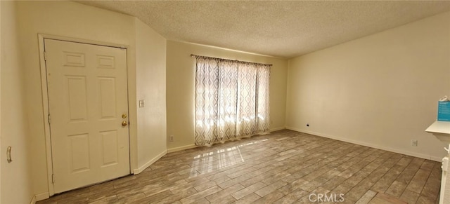 entrance foyer featuring a textured ceiling, baseboards, and wood finished floors