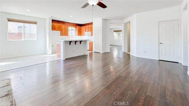 unfurnished living room featuring baseboards, a ceiling fan, wood finished floors, and recessed lighting