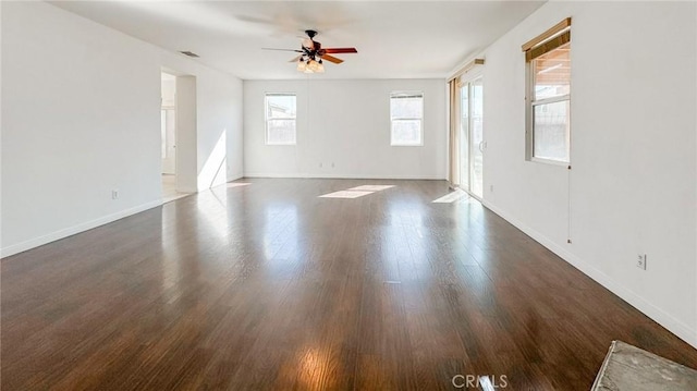 empty room featuring dark wood-style floors, ceiling fan, visible vents, and baseboards