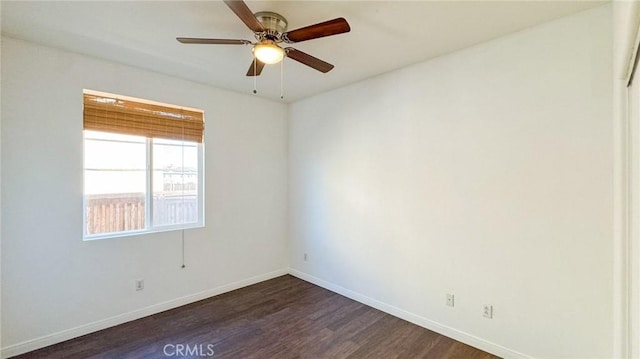 spare room with dark wood-style floors, a ceiling fan, and baseboards