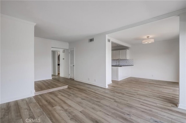unfurnished living room featuring baseboards, visible vents, and light wood-style floors