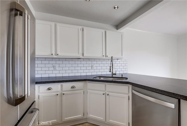 kitchen with a sink, stainless steel appliances, tasteful backsplash, beam ceiling, and white cabinetry