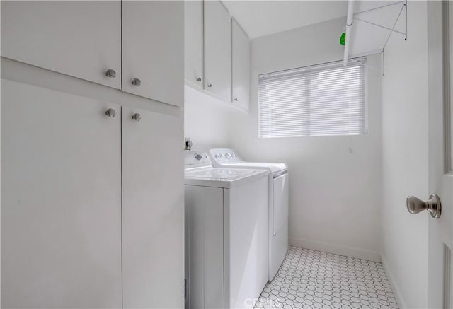 laundry room featuring washing machine and dryer, light floors, cabinet space, and baseboards