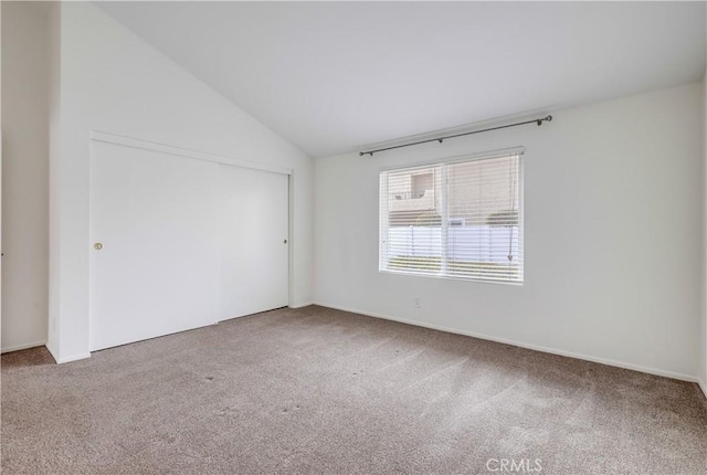 unfurnished room with lofted ceiling, carpet flooring, and baseboards