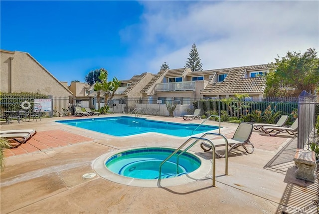 pool featuring a patio area, a community hot tub, and fence