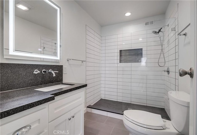 bathroom featuring tile patterned floors, vanity, toilet, and tiled shower
