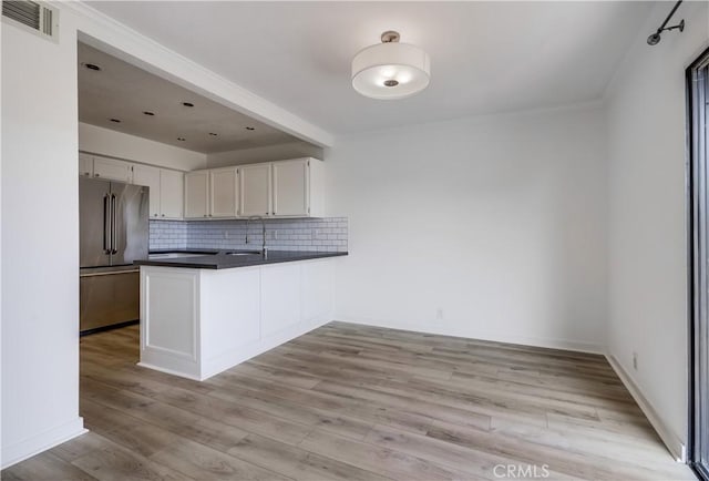 kitchen featuring high quality fridge, visible vents, a sink, dark countertops, and tasteful backsplash