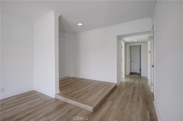 spare room with crown molding, wood finished floors, and baseboards