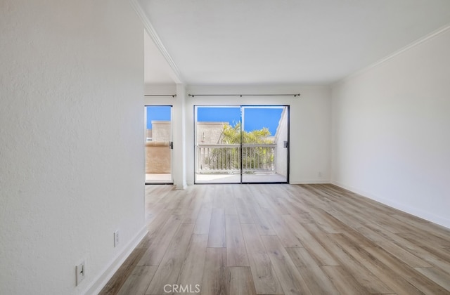 empty room with wood finished floors, baseboards, and ornamental molding