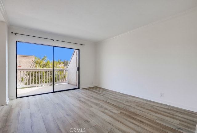 spare room with ornamental molding, light wood-style flooring, and baseboards