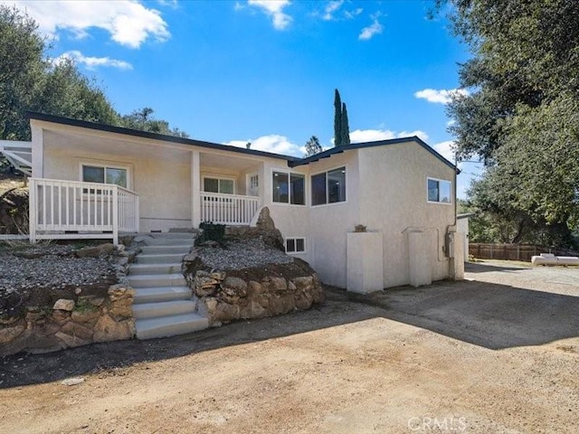 view of front of property featuring driveway, stairs, a porch, and stucco siding