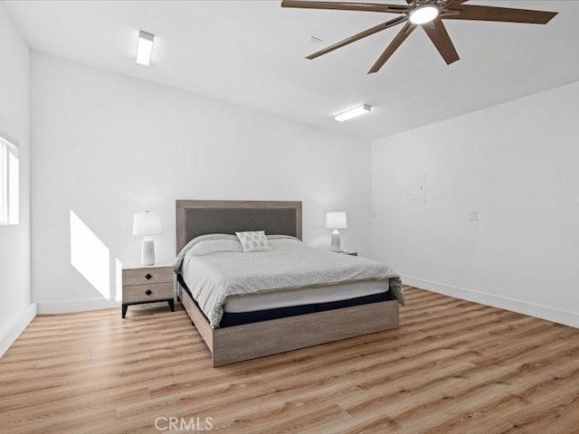 bedroom with light wood-type flooring, a ceiling fan, and baseboards