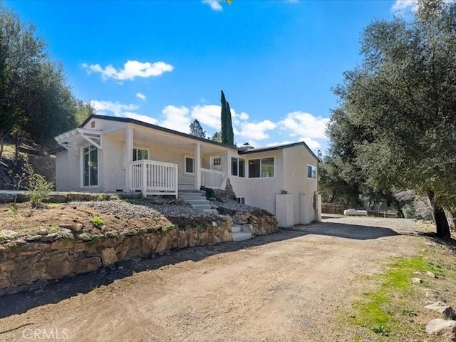 ranch-style house with driveway, a porch, and stucco siding