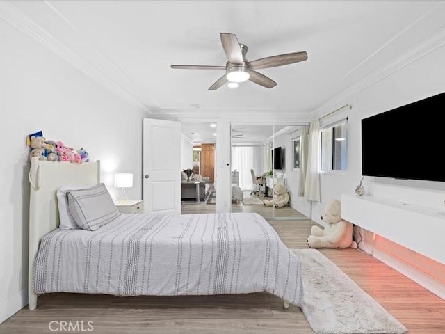 bedroom with ceiling fan, a closet, wood finished floors, and crown molding