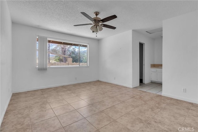 tiled spare room featuring a textured ceiling, a ceiling fan, and baseboards