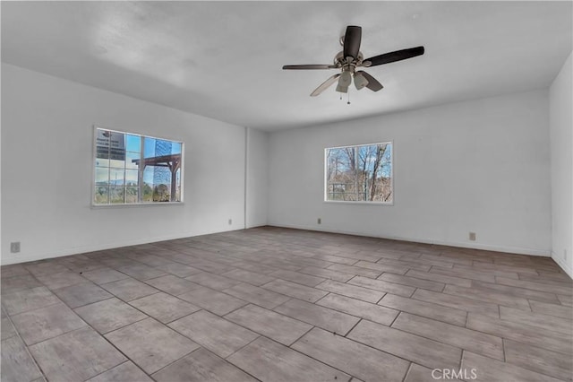 unfurnished room with a ceiling fan and baseboards