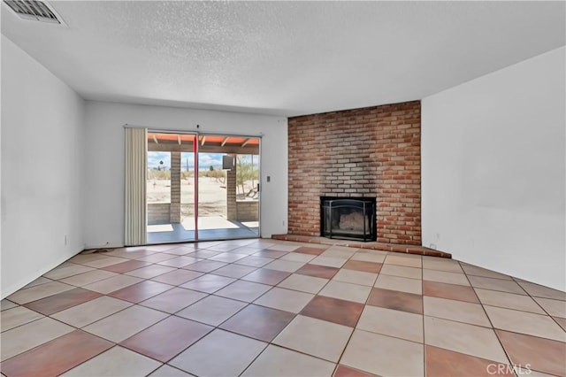 unfurnished living room featuring a brick fireplace, tile patterned flooring, visible vents, and a textured ceiling