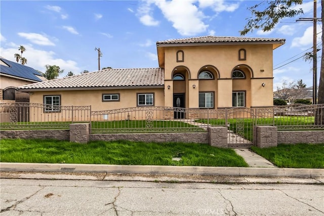 mediterranean / spanish-style house with a fenced front yard, a tiled roof, and stucco siding