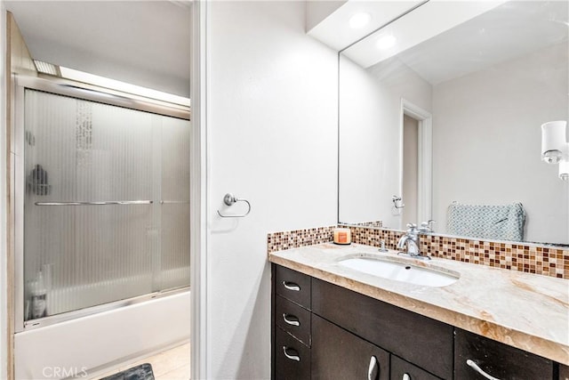 full bathroom featuring tasteful backsplash, combined bath / shower with glass door, and vanity