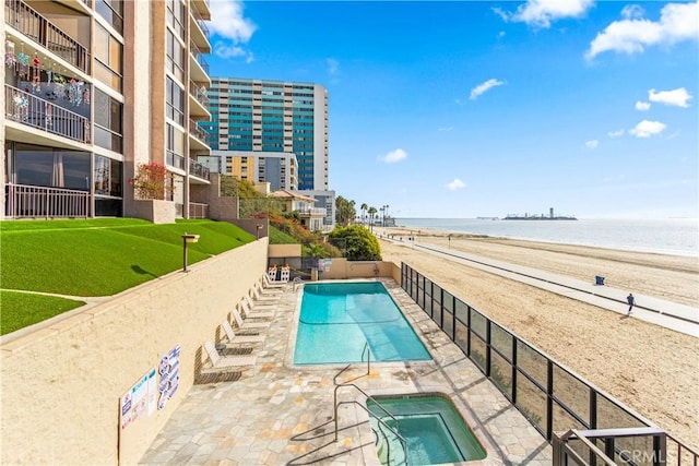 community pool with a view of the beach, a patio area, and a water view