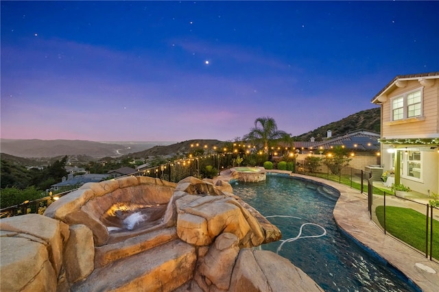 view of pool with fence, a fenced in pool, an in ground hot tub, a patio area, and a mountain view