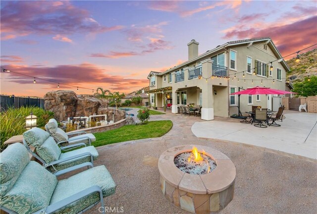 2514 Bulrush Cir, Corona, CA 92882 - back of property at dusk with a balcony, a patio, fence, and stucco siding