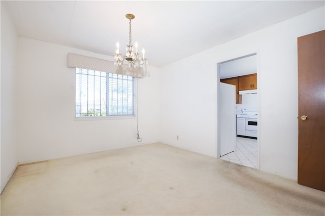 spare room featuring an inviting chandelier and light colored carpet