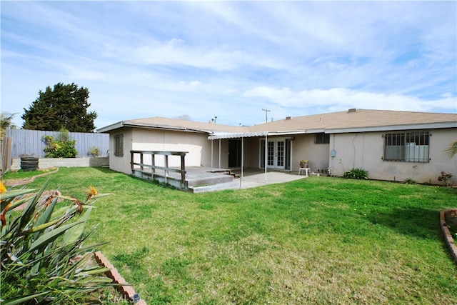 rear view of house featuring a lawn, a patio, a fenced backyard, french doors, and stucco siding