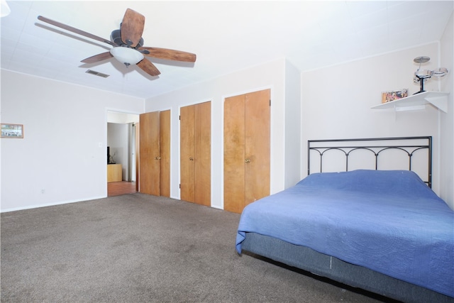 bedroom with multiple closets, visible vents, carpet floors, and a ceiling fan