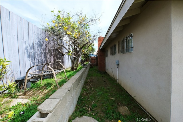 view of side of home with fence and stucco siding