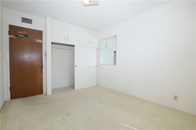 unfurnished bedroom with a closet, visible vents, and light carpet