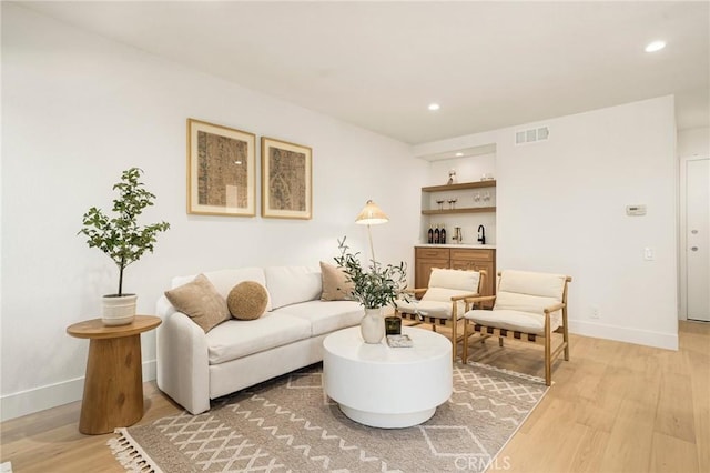 living area with light wood-type flooring, visible vents, baseboards, and recessed lighting